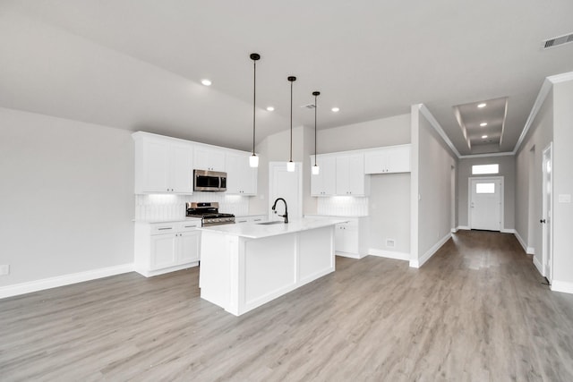 kitchen featuring pendant lighting, a kitchen island with sink, light hardwood / wood-style flooring, white cabinetry, and stainless steel appliances