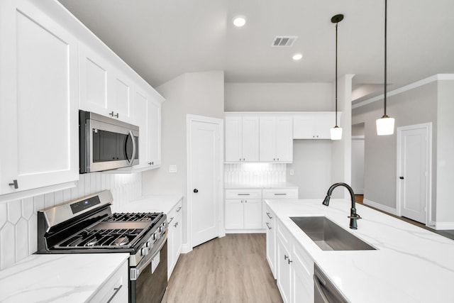 kitchen featuring backsplash, stainless steel appliances, sink, decorative light fixtures, and white cabinets