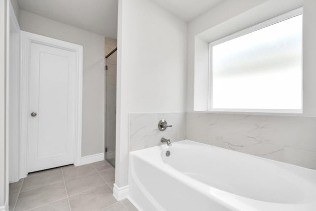 bathroom featuring independent shower and bath, tile patterned flooring, and a healthy amount of sunlight