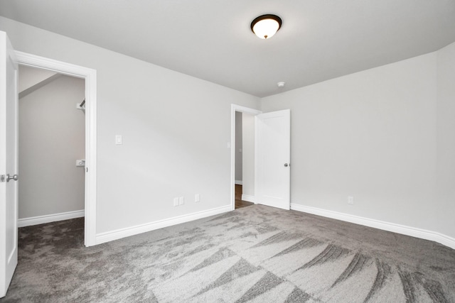 unfurnished bedroom featuring dark colored carpet, a spacious closet, and a closet