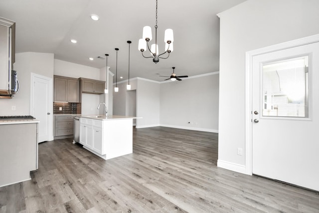 kitchen featuring wood-type flooring, pendant lighting, ceiling fan with notable chandelier, and an island with sink