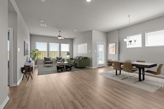 interior space with ceiling fan with notable chandelier and light wood-type flooring