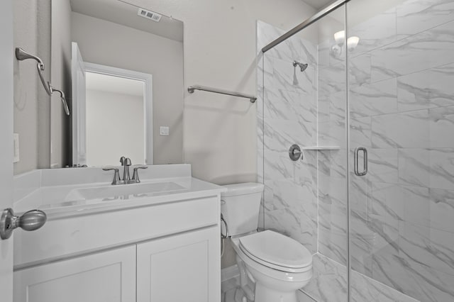 bathroom featuring vanity, a shower with shower door, and toilet