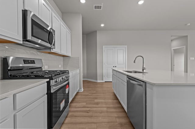 kitchen featuring light hardwood / wood-style floors, a kitchen island with sink, sink, stainless steel appliances, and white cabinets