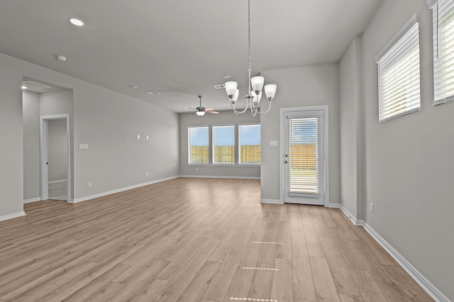 unfurnished dining area featuring ceiling fan with notable chandelier and light hardwood / wood-style flooring