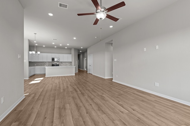 unfurnished living room featuring ceiling fan with notable chandelier and light wood-type flooring