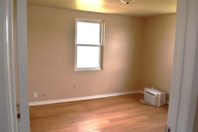 empty room with plenty of natural light, a wall mounted air conditioner, and light hardwood / wood-style floors