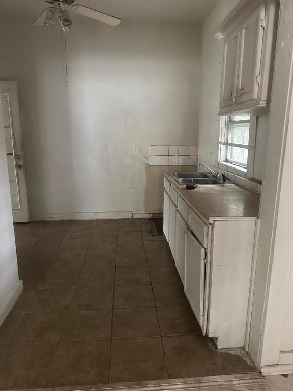 kitchen featuring ceiling fan, sink, white cabinets, and dark tile patterned flooring