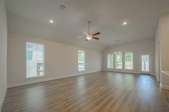 spare room with lofted ceiling, a healthy amount of sunlight, light wood-type flooring, and ceiling fan with notable chandelier