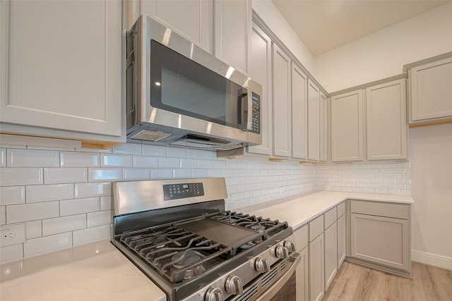 kitchen featuring tasteful backsplash, gray cabinetry, stainless steel appliances, and light hardwood / wood-style floors