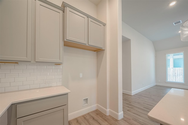 kitchen with gray cabinetry, decorative backsplash, and light hardwood / wood-style flooring