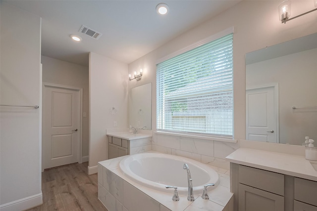 bathroom featuring tiled bath, hardwood / wood-style floors, and vanity