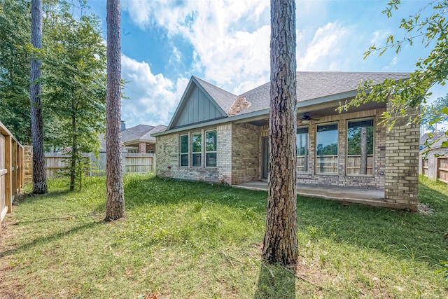 rear view of house featuring a lawn and ceiling fan