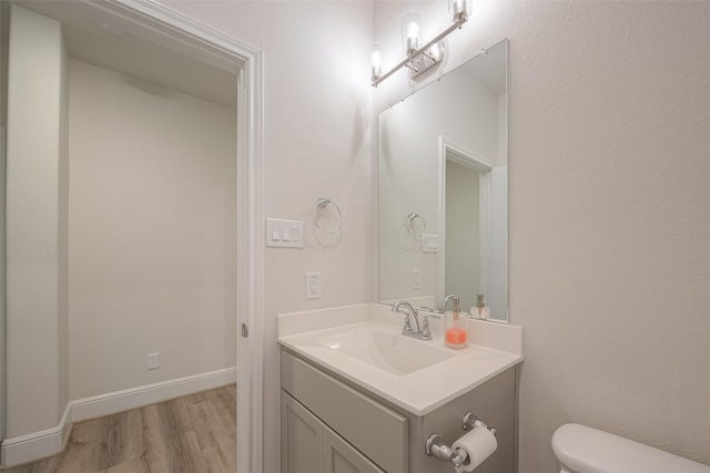 bathroom featuring toilet, vanity, and hardwood / wood-style flooring