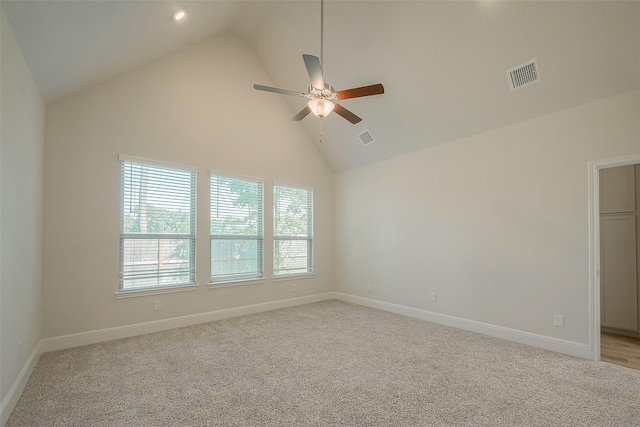 carpeted spare room with ceiling fan and high vaulted ceiling