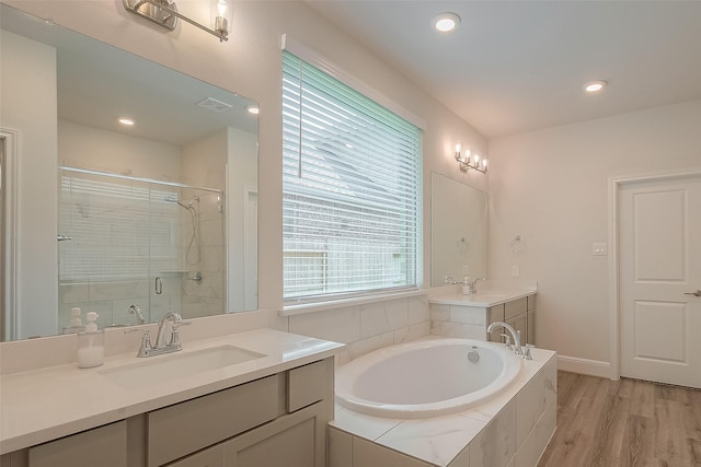 bathroom featuring wood-type flooring, vanity, and shower with separate bathtub