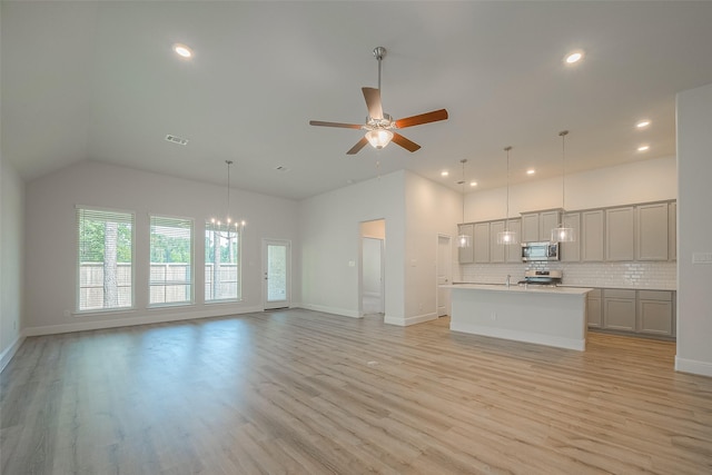 kitchen with gray cabinetry, decorative backsplash, a kitchen island with sink, appliances with stainless steel finishes, and light wood-type flooring