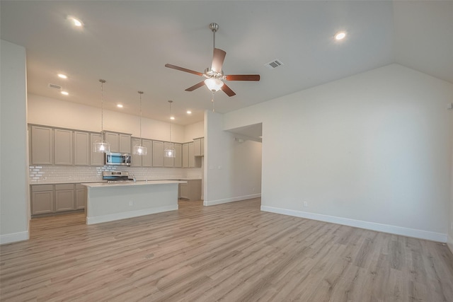 kitchen with gray cabinetry, a center island with sink, light hardwood / wood-style flooring, tasteful backsplash, and stainless steel appliances