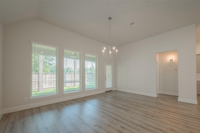 unfurnished room with lofted ceiling, light wood-type flooring, and a chandelier