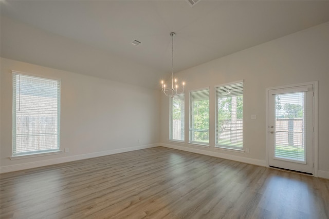 unfurnished room featuring a wealth of natural light, light hardwood / wood-style flooring, and an inviting chandelier