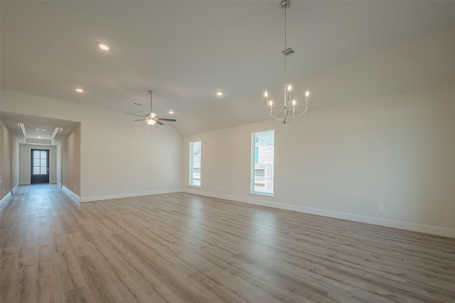 empty room featuring ceiling fan with notable chandelier, light hardwood / wood-style floors, and plenty of natural light