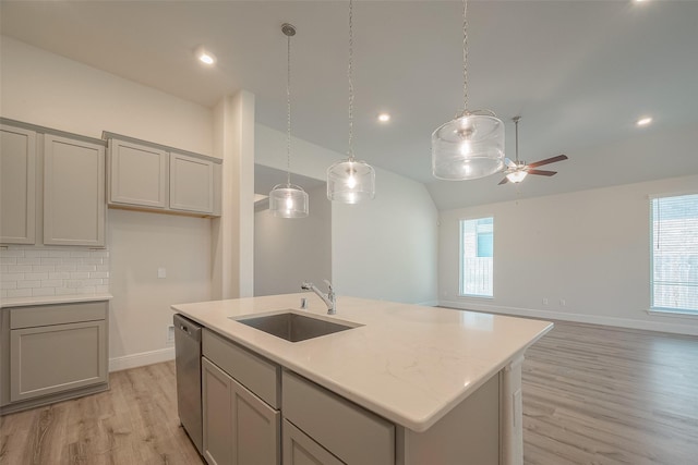 kitchen featuring gray cabinetry, dishwasher, sink, a center island with sink, and light wood-type flooring