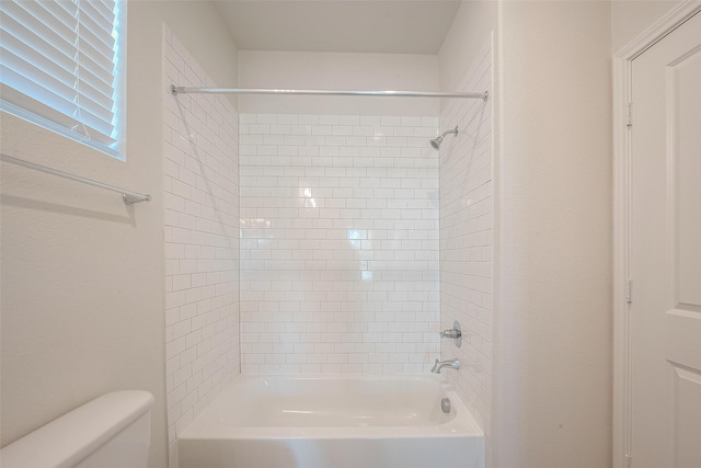 bathroom with toilet and tiled shower / bath