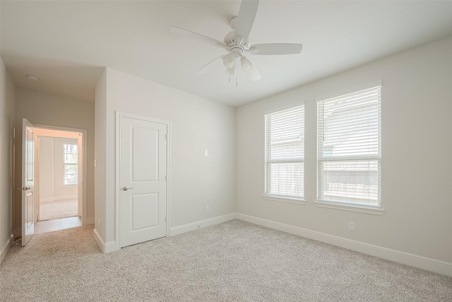 spare room with ceiling fan and light carpet