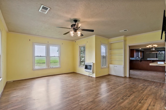 unfurnished living room with ornamental molding, heating unit, ceiling fan with notable chandelier, and hardwood / wood-style floors