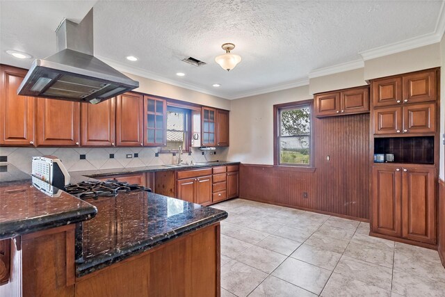 kitchen featuring island range hood, kitchen peninsula, dark stone counters, a textured ceiling, and crown molding