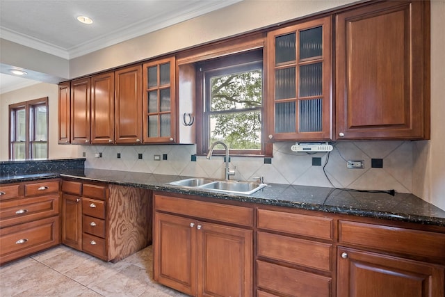 kitchen featuring ornamental molding, decorative backsplash, dark stone countertops, and sink