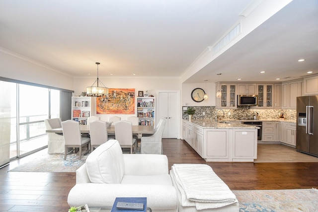 living room with dark hardwood / wood-style flooring, sink, ornamental molding, and a notable chandelier