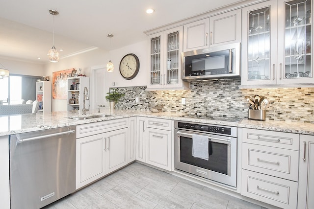 kitchen with kitchen peninsula, appliances with stainless steel finishes, backsplash, sink, and decorative light fixtures