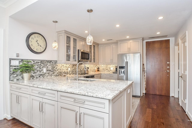 kitchen featuring pendant lighting, sink, dark hardwood / wood-style floors, light stone countertops, and appliances with stainless steel finishes