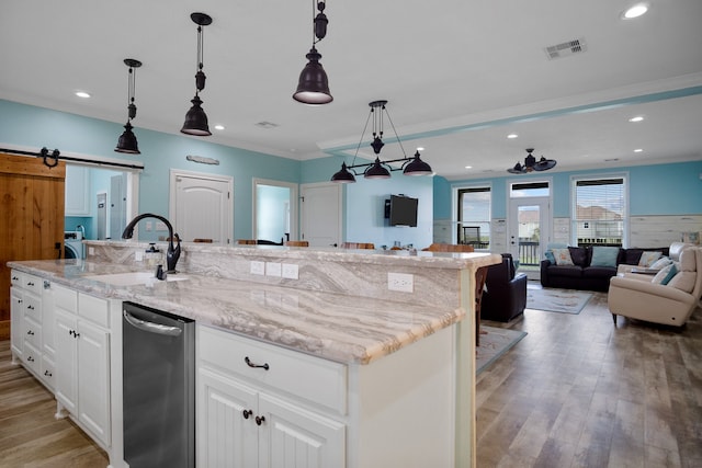 kitchen featuring hanging light fixtures, an island with sink, and light wood-type flooring