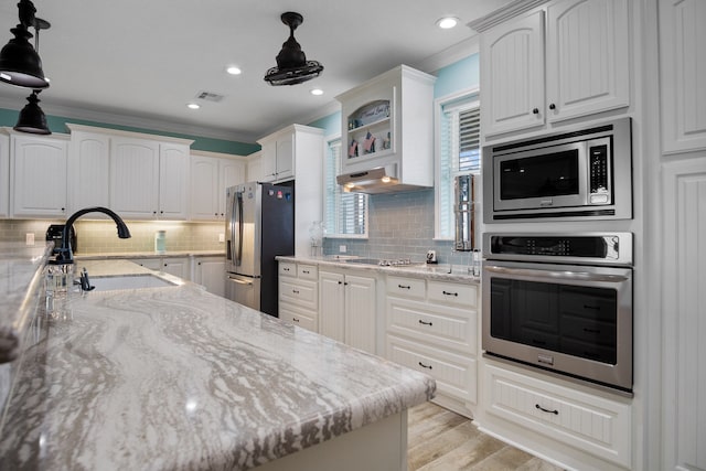 kitchen with light hardwood / wood-style floors, pendant lighting, light stone counters, backsplash, and appliances with stainless steel finishes