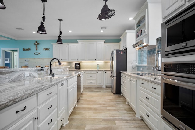 kitchen with backsplash, crown molding, white cabinetry, light wood-type flooring, and appliances with stainless steel finishes