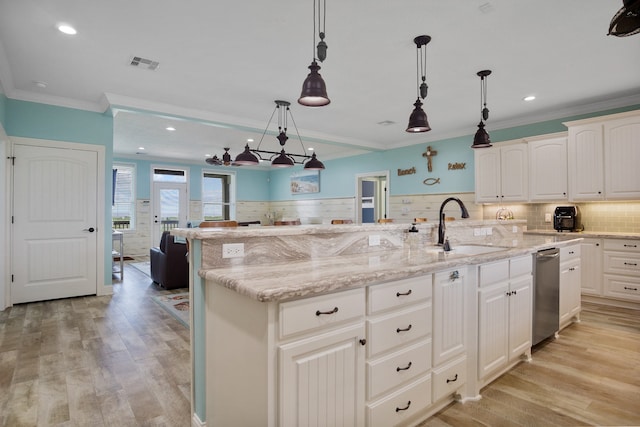 kitchen featuring a kitchen island with sink, backsplash, pendant lighting, and light wood-type flooring