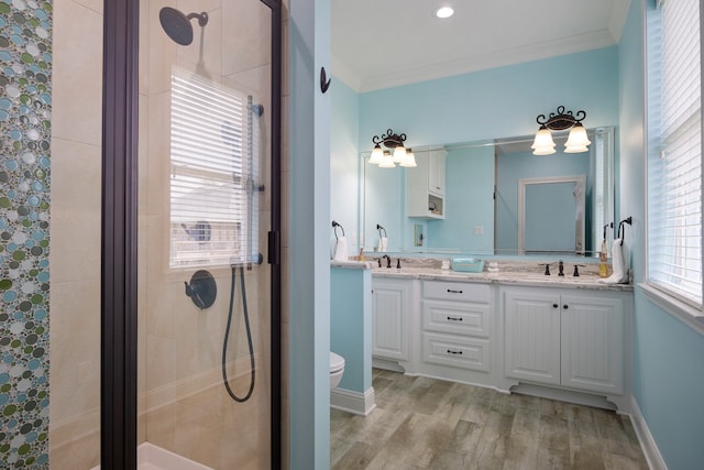 bathroom featuring vanity with extensive cabinet space, toilet, hardwood / wood-style flooring, crown molding, and double sink