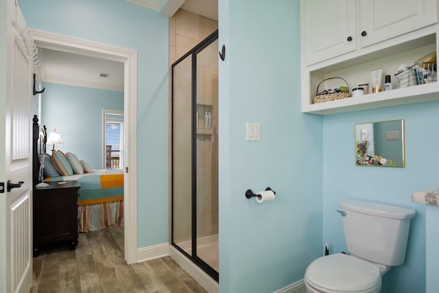 bathroom featuring crown molding, hardwood / wood-style flooring, a shower with shower door, and toilet