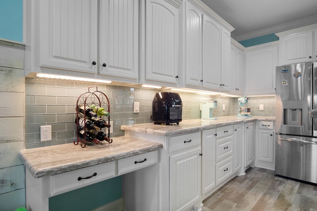 kitchen featuring white cabinetry, stainless steel fridge with ice dispenser, light hardwood / wood-style floors, light stone counters, and tasteful backsplash