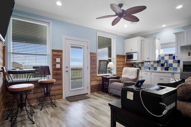 living room featuring crown molding, sink, light wood-type flooring, and ceiling fan