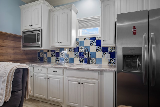 kitchen with light stone countertops, tasteful backsplash, stainless steel appliances, sink, and white cabinets