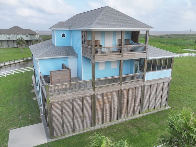 rear view of property featuring a lawn and a balcony