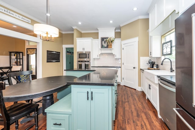 kitchen with appliances with stainless steel finishes, a center island, pendant lighting, white cabinetry, and blue cabinets