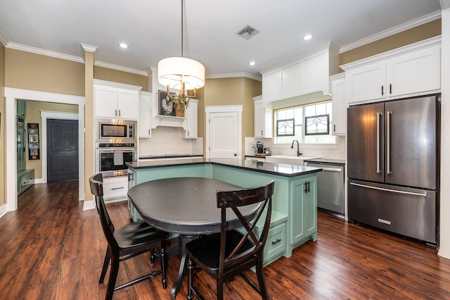 kitchen featuring pendant lighting, stainless steel appliances, a kitchen island, backsplash, and white cabinets