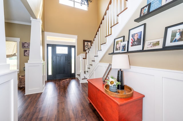 foyer with ornamental molding, dark wood-type flooring, and decorative columns