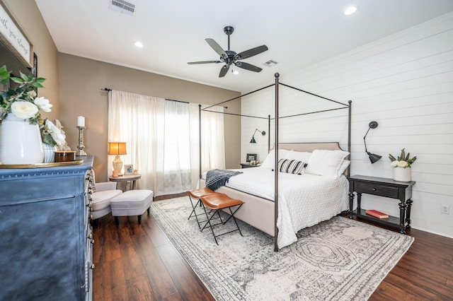 bedroom featuring ceiling fan, dark wood-type flooring, and wood walls