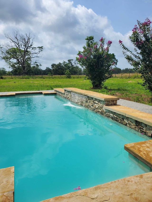 view of pool featuring a lawn, pool water feature, and a rural view