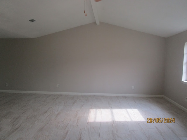 spare room featuring lofted ceiling with beams and light hardwood / wood-style floors